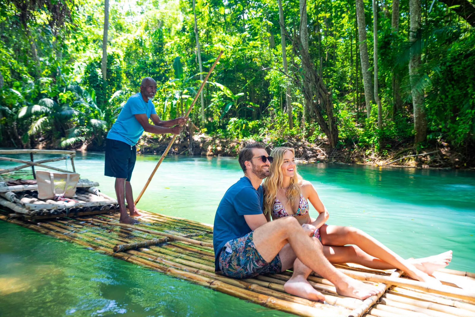 Couple relaxing on a bamboo raft on a calm green river