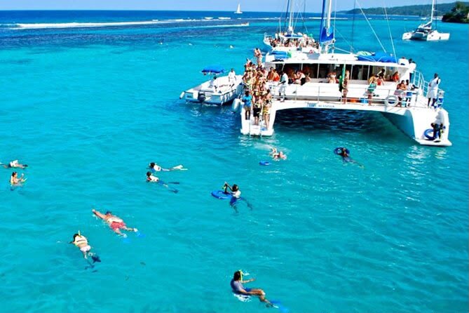 Swimmers snorkelling beside a catamaran on turquoise water