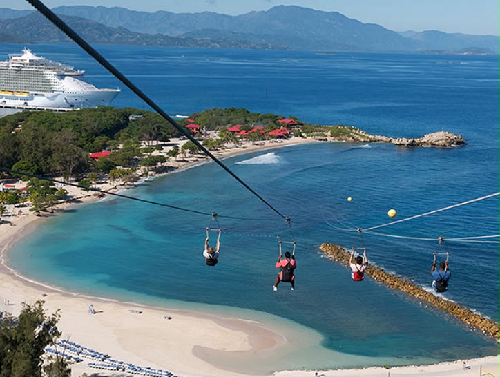 Riders ziplining over a turquoise bay in Jamaica